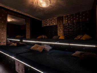 The couples-only play room, with quilted velvet walls, a full-length mirror, and low platform beds lit by LED strip lighting